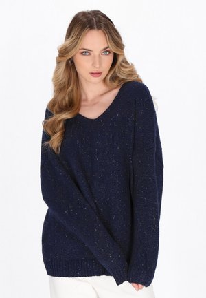Marineblauem Strickpullover mit lockerer Passform, V-Ausschnitt und gerippten Bündchen. Der strukturierte Garn hat subtile metallische Sprenkel.