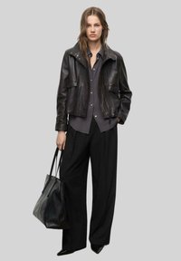 Czarna skórzana kurtka o dopasowanym kroju; założona na ciemnoszary T-shirt. W zestawie z czarnymi spodniami o wysokim stanie i czarną torebką na ramię.