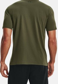 Olivengrøn t-shirt med korte ærmer og rund hals, med ensfarvet design og glat tekstur. Logo trykt på øverste del af ryggen.