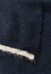 Navy woolen fabric with a textured surface, featuring a cream-colored edge detail. Fibers are visible along the seams.