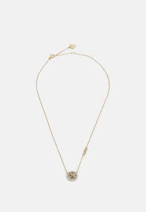 Colar de corrente de ouro com um pendente circular que apresenta um emblema central e uma borda de pedras semelhantes a diamantes. Inclui um fecho com uma etiqueta da marca.
