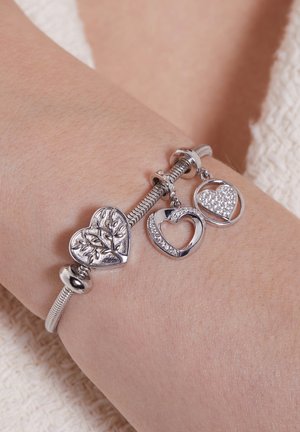 Zilveren bedelarmband met een gestructureerd hart, een gepolijst hart en een hart bezet met heldere stenen, met een flexibele schakelontwerp.