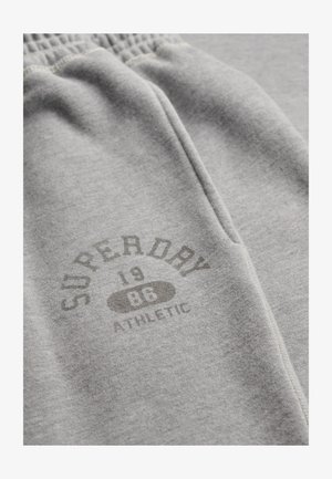 Light grey sweatpants with an elastic waistband and a printed logo reading "Superdry 1986 Athletic" near the pocket.