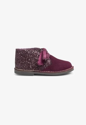 Stivale alla caviglia in suede bordeaux con una parte superiore glitterata di colore viola, caratterizzato da un accento a fiocco in satin e una suola cucita. Texture liscia con decorazioni lucenti.