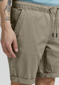 Khaki shorts med elastisk talje, snøre lukning og oprullede ben. Fremstillet af letvægtsstof med sidelommer.