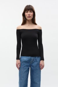 Juoda ilgomis rankovėmis off-the-shoulder palaidinė, pagaminta iš tamprios medžiagos, derinama su laisvai krentančiomis šviesiai mėlynomis džinsinėmis kelnėmis. Paprastas dizainas, be raštų.