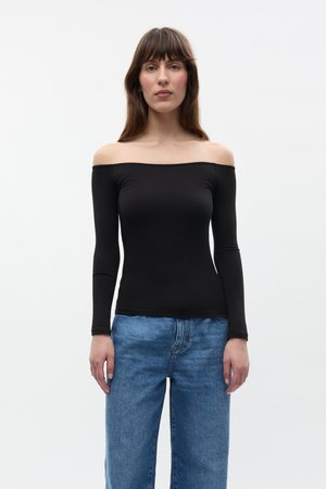 Zwarte langmouw off-shoulder top van rekbaar materiaal, gecombineerd met lichtblauwe spijkerbroek in een relaxed fit. Eenvoudig ontwerp, geen patronen.