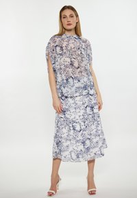 Rochie cu imprimeu floral dintr-un material transparent, cu nuanțe de albastru și alb. Dispune de un decolteu înalt și fante pe mâneci. Fustă lungă, fluidă, până la glezne.
