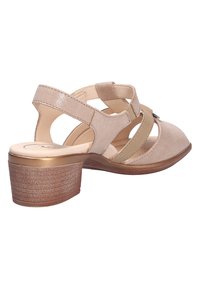 Beige Absatzsandale mit offenen Seiten, glattem, wildlederähnlichem Stoff, Kreuzgurten und einem niedrigen Blockabsatz mit einer strukturierten Gummisohle.