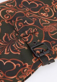 Μαύρος ύφασμα με περίπλοκα πορτοκαλί και κόκκινα σπειροειδή μοτίβα. Διαθέτει κουμπί και λεπτομέρεια ιμάντα για κλείσιμο. Υφή επιφάνειας, διπλωμένη άκρη.