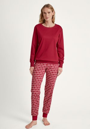 Red long-sleeve top with a round neckline and subtle stitching, paired with red and white checkered pajama pants with ribbed cuffs.