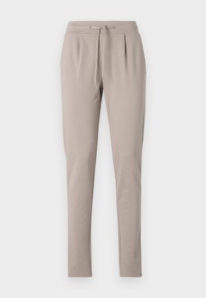 Beige joggingsbyxor med dragsko i midjan, smalnande ben och veckat framstycke. Tillverkade av mjukt, lätt material.