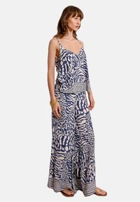 Top senza maniche a righe blu navy e crema, abbinato a pantaloni a gamba larga, caratterizzato da una vestibilità morbida e decorazioni sui bordi. Tessuto leggero.