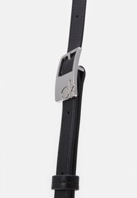 Cintura in pelle nera con fibbia rettangolare in tono argento con logo, lunghezza regolabile con perforazioni lungo la cintura.