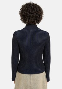 Marineblauwe geribbelde trui met blauwe accenten, voorzien van een hoge kraag en een smalle pasvorm. Gestructureerde breiwerkstof, lange mouwen.