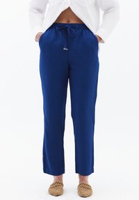 Koninklijkblauwe, losse broek met een elastische tailleband en verstelbaar trekkoord. Gemaakt van een lichtgewicht stof met zijzakken.
