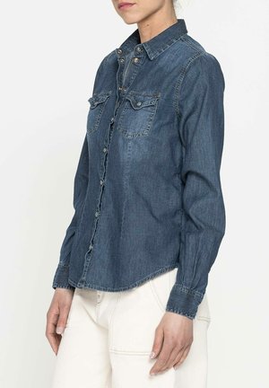 Camicia in denim scuro con bottoni, due tasche sul petto, maniche lunghe e orlo curvo. Presenta bottoni metallici e dettagli di cucitura sottili.
