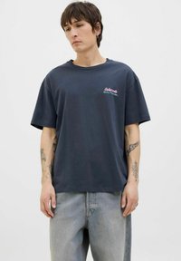 Mørkegrå bomulds T-shirt med en afslappet pasform, der har farverig brodering med "Colorado Rocky Mountains" på venstre bryst.