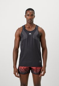 Sort træningstop med mesh-detaljer og et logo, parret med røde og sorte shorts med mønster og hvid tekst. Glat stof, tætsiddende design.
