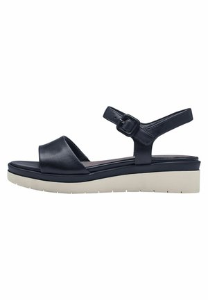Sandale en cuir noir avec une semelle blanche épaisse, sangle ajustable avec boucle carrée, design ouvert à l'avant et texture lisse.