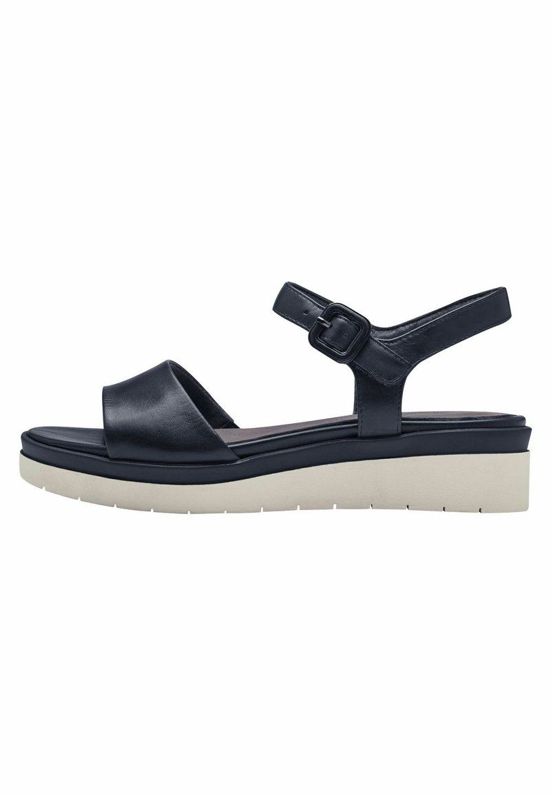 Sandale en cuir noir avec une semelle blanche épaisse, sangle ajustable avec boucle carrée, design ouvert à l'avant et texture lisse.