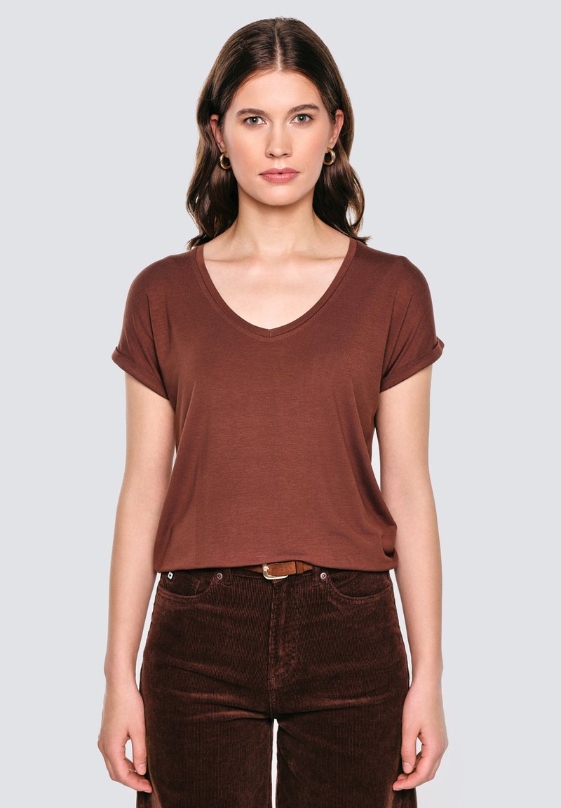 Brązowa, krótkorękawowa koszulka V-neck wykonana z miękkiego materiału, zestawiona z ciemnobrązowymi sztruksowymi spodniami. Prosty design z podwiniętymi mankietami rękawów.