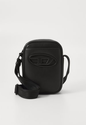 Petit sac bandoulière rectangulaire noir avec une sangle en tissu réglable et un logo ovale embossé sur le panneau avant.