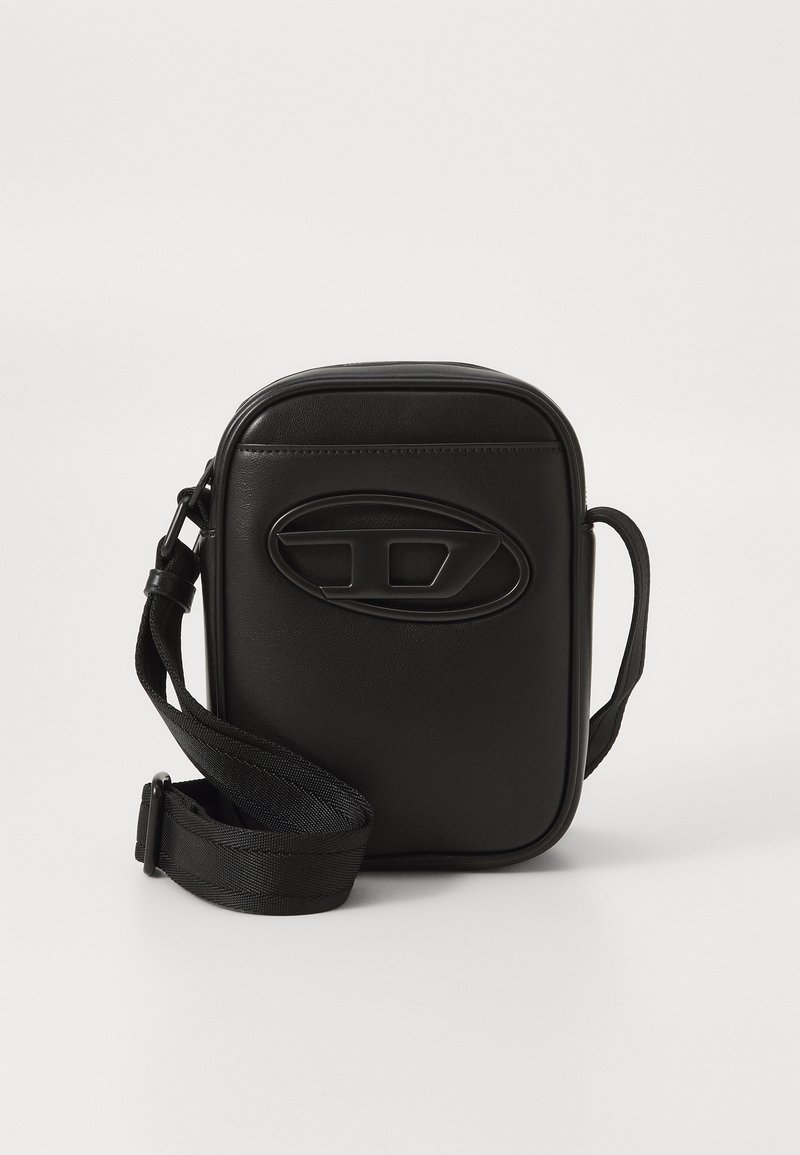 Petit sac bandoulière rectangulaire noir avec une sangle en tissu réglable et un logo ovale embossé sur le panneau avant.