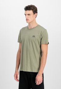 Olivegrünes Baumwoll-T-Shirt mit Rundhalsausschnitt, kurzen Ärmeln und einem kleinen schwarzen Logo auf der Brust. Slim Fit mit glatter Textur.