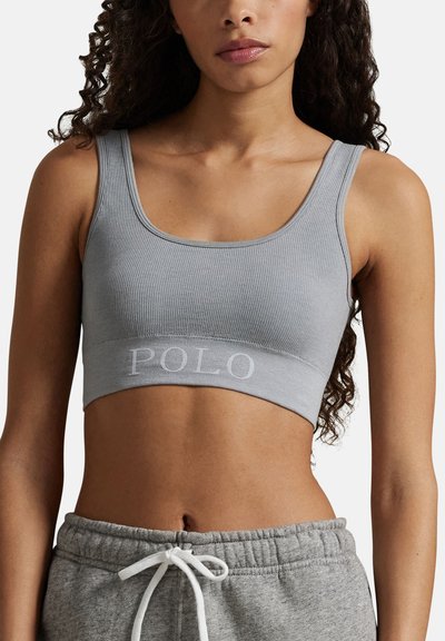 Grå ribbad croptop med ett brett band med texten "POLO" i ljusgrått. Materialet verkar mjukt med en figurnära design.