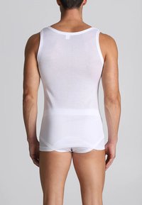 Canotta bianca senza maniche realizzata in un tessuto morbido ed elastico. Forma aderente con dettagli di cucitura minimi e spalline sottili.