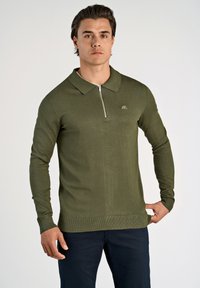 Polo a maniche lunghe verde oliva con colletto, zip frontale a metà e polsini a coste. Presenta un piccolo logo sul petto. Tessuto a maglia liscia.