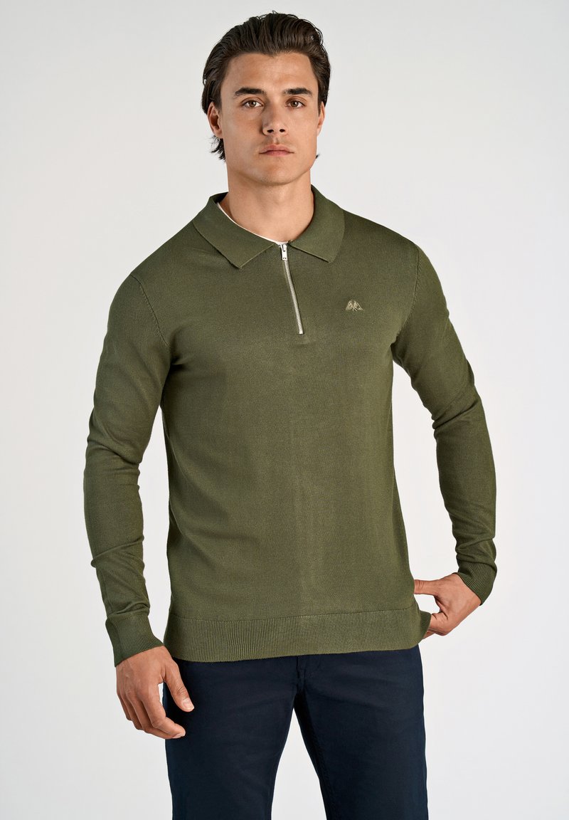 Polo a maniche lunghe verde oliva con colletto, zip frontale a metà e polsini a coste. Presenta un piccolo logo sul petto. Tessuto a maglia liscia.