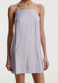 Liliowa sukienka na ramiączkach z cienkimi paskami, ozdobiona białym wzorem kwiatowym. Miękka, lekka tkanina o luźnym kroju i prostym dolnym wykończeniu.