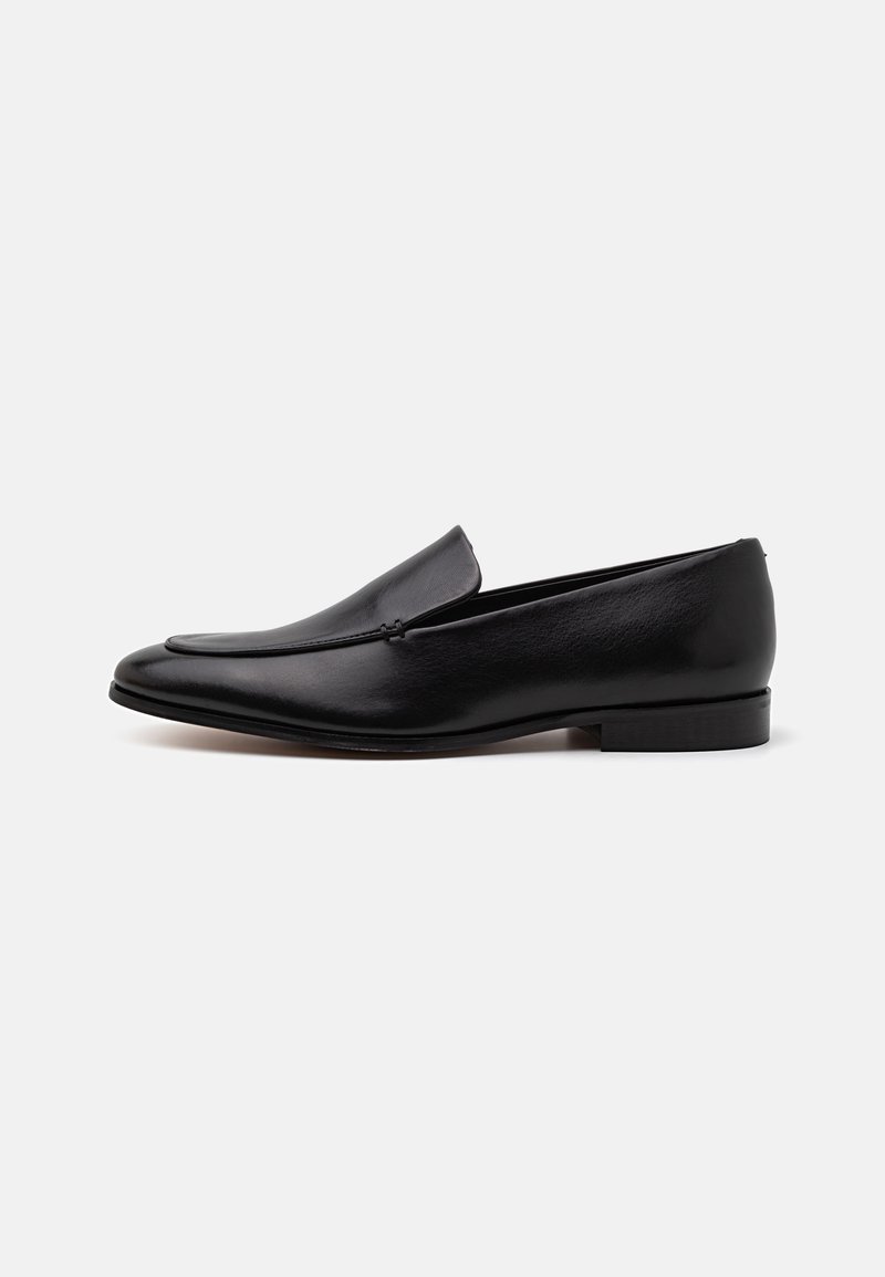 Black leather loafers with a sleek design, elongated shape, and minimalistic stitch detail. Slim, low heel for stability.