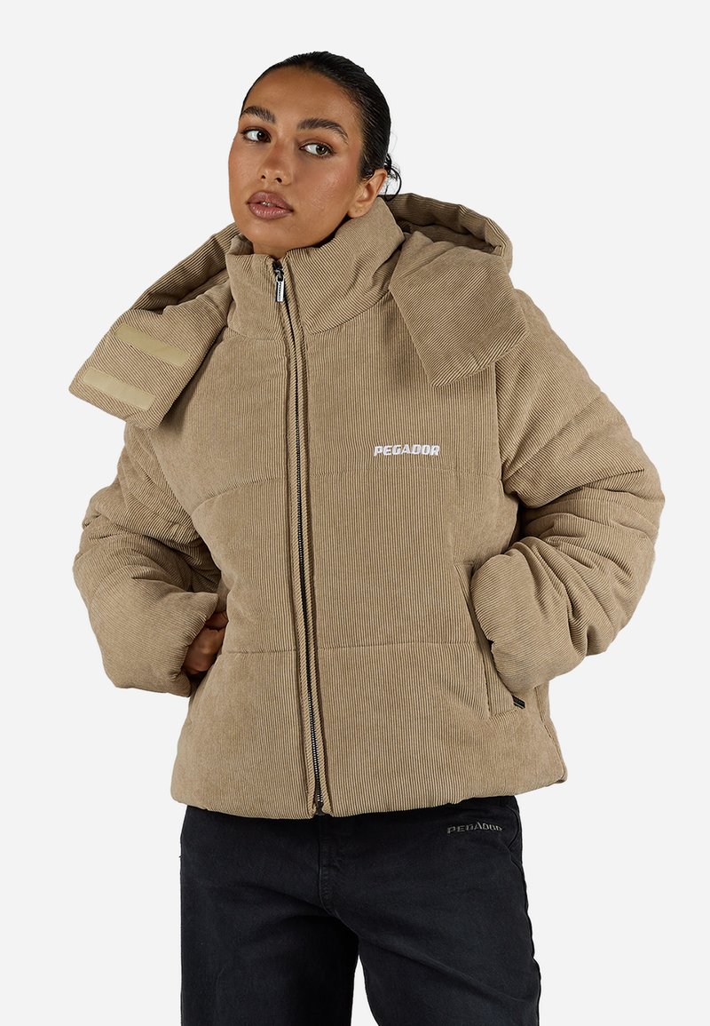 Ruda plombiruota striukė su didele kapuce, aukštu apykakle ir priekiu užtraukiama. Su šoninėmis kišenėmis ir subtiliu logotipu. Storis, tekstūruotas audinys.