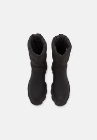 Černé waterproof boty s prošívaným svrškem, zaoblenou špičkou, texturovanou podrážkou a měkkým vnitřkem. Design zahrnuje nízký svršek.