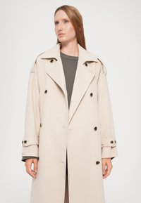 Beige Wollmischung Mantel mit doppelter Knopfleiste, großen Revers und Knopfakzenten. Verfügt über aufgerollte Ärmel und eine gerade Silhouette.