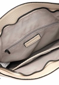Intérieur d'un sac à main en cuir beige avec un motif texturé, doté d'une doublure en tissu gris, d'une poche zippée et d'une étiquette de marque.