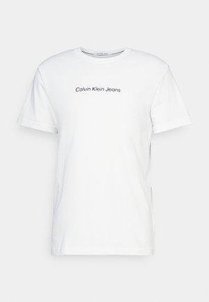 T-shirt blanc à manches courtes et col rond avec le logo "Calvin Klein Jeans" imprimé en noir sur la poitrine.