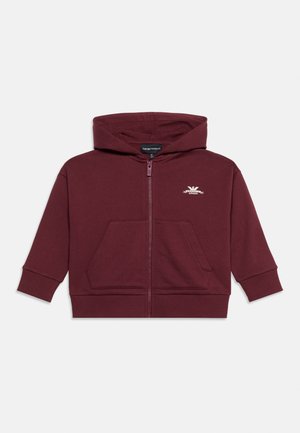 Bordeauxrode capuchontrui met ritssluiting aan de voorkant, zakken en een klein wit logo op de linkerborst.