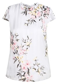 Vit kortärmad blus med volangkrage, med ett blommönster i rosa, gult och grönt på en texturerad bakgrund.