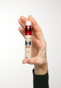 Maybelline Concealer in einem transparenten Tube mit einem roten Deckel, ausgestattet mit einer abgerundeten Applikatorspitze; Farbton 00 auf dem Körper gekennzeichnet.