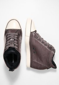Graue Stoff-Sneaker mit weißer Gummikappe, strukturiertem Obermaterial, runden Schnürsenkeln und schwarzem Innenfutter. Verfügt über zwei schwarze Knöpfe an der Seite.