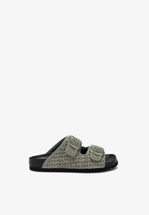Enkelt grå-grøn tekstureret slip-sandal med to justerbare spænderemme og sort sål, vist på en hvid baggrund.