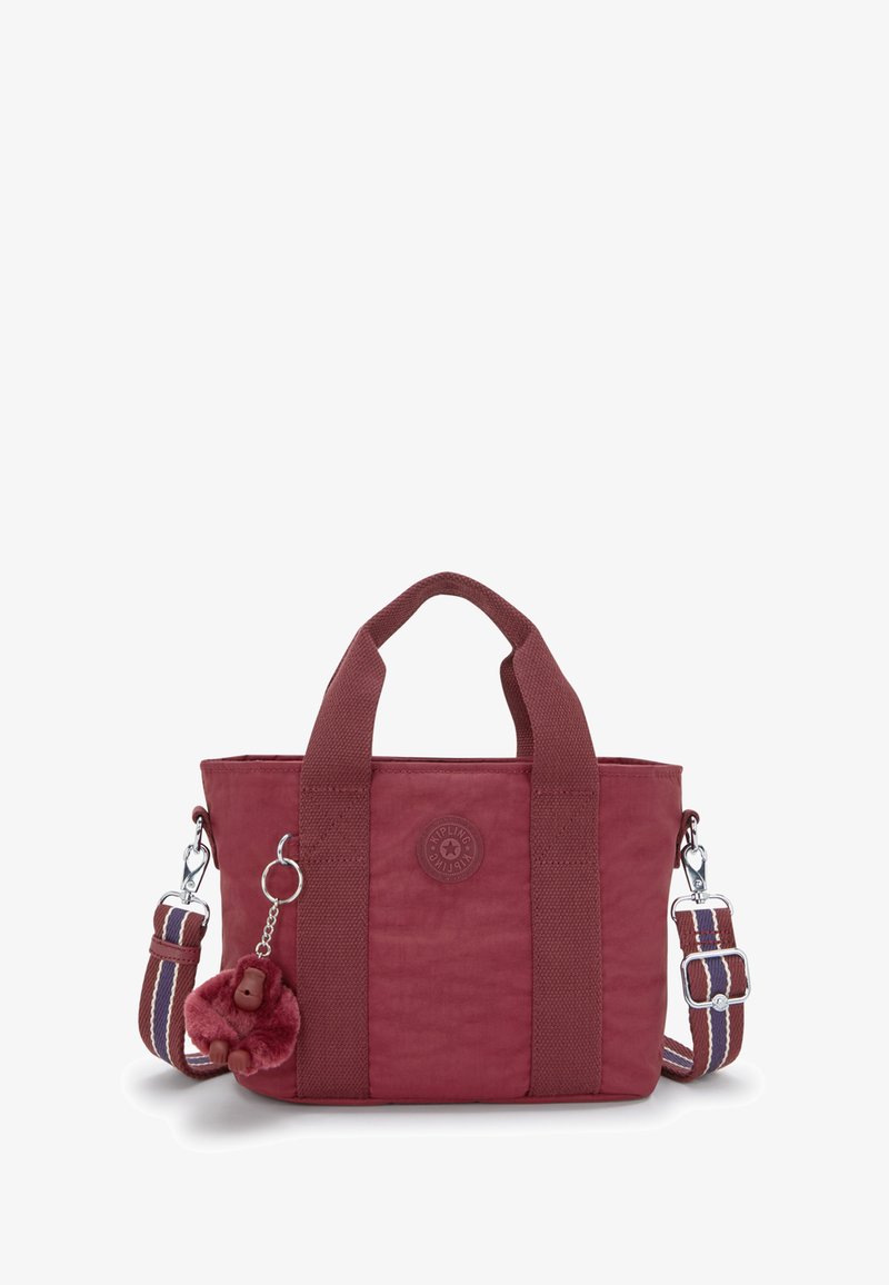 Borsa a tracolla di tessuto rosso con manici corti e una tracolla staccabile a righe. Presenta una patch con logo e un charm di un animale peloso.