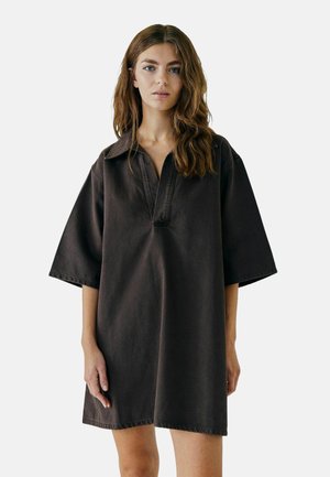 Donker oversized overhemdjurk van denim, met een kraag, korte mouwen en een losse pasvorm. Het ontwerp heeft minimale stiknaden.