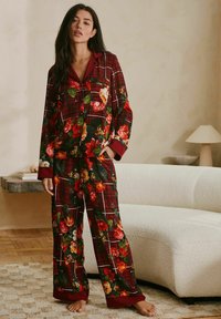 Floral plaid pajama set in red, green, and yellow. Features a button-up top with a collar and long sleeves, paired with matching pants.