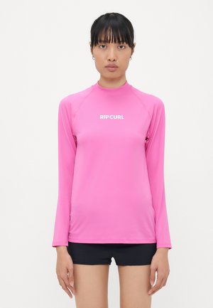 Long-sleeve pink rash guard made of smooth, stretchy fabric with a high collar and white "RIP CURL" logo on the front.