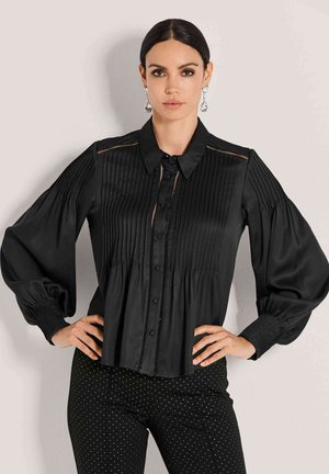 Schwarze, plissierte Bluse mit kragenähnlichem Hals, Knopfleiste und weiten Ärmeln. Glattes Gewebe mit subtiler Schattierung und filigranen Details.